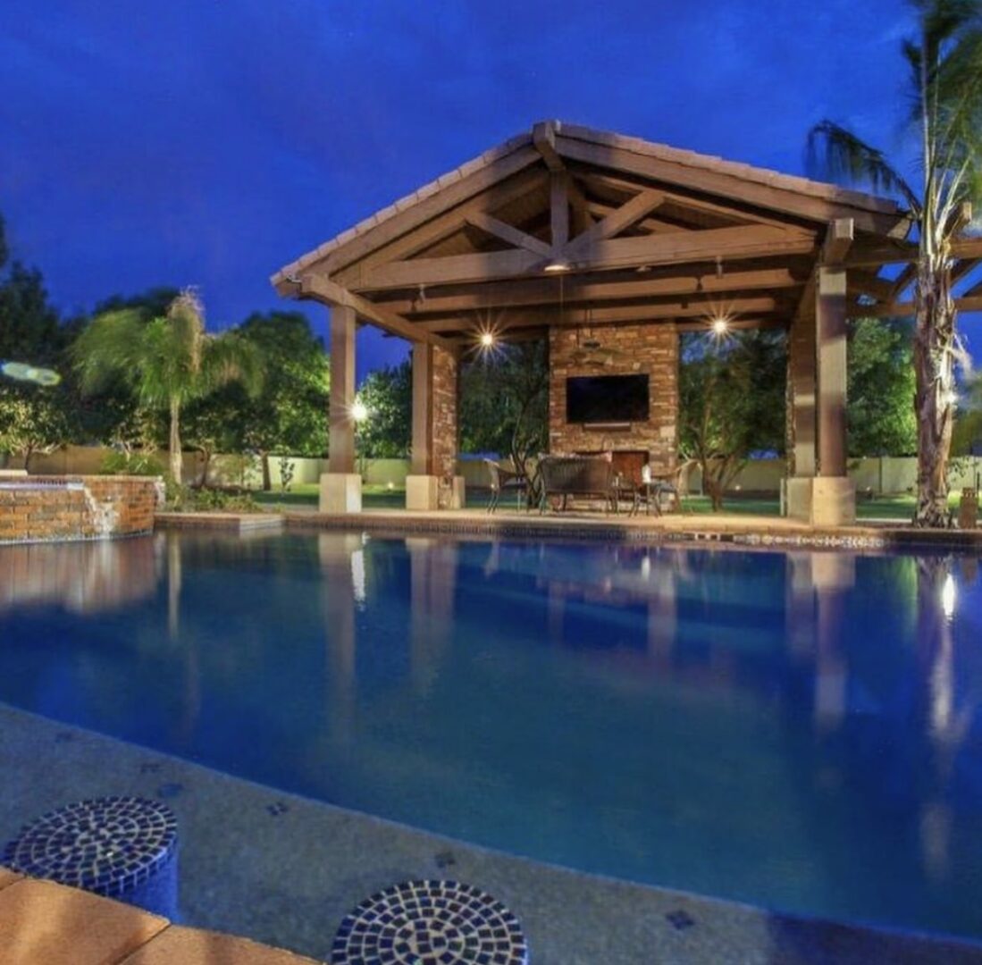 A pool with an outdoor pavilion and seating area.